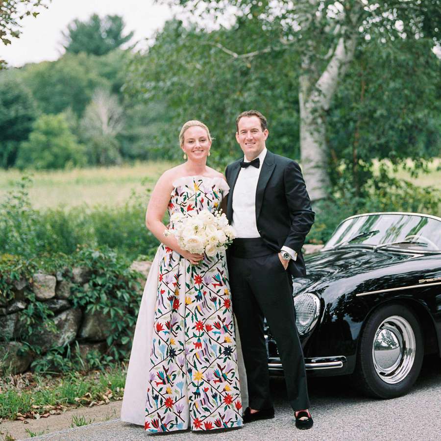 Bride Alex in multicolor Carolina Herrera printed dress and groom Eric in tuxedo with black Porsche